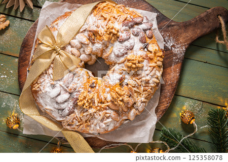 Bolo Rainha, a celebratory ring cake garnished with almonds, nuts, dried fruits, fruits raisins and dusted with powdered sugar, perfect for festive occasions like Christmas and New Year. Top view Bolo Rainha, a celebratory ring cake garnished with almonds, nuts, dried fruits, fruits raisins and dusted with powdered sugar, perfect for festive occasions like Christmas and New Year. Top view 125358078