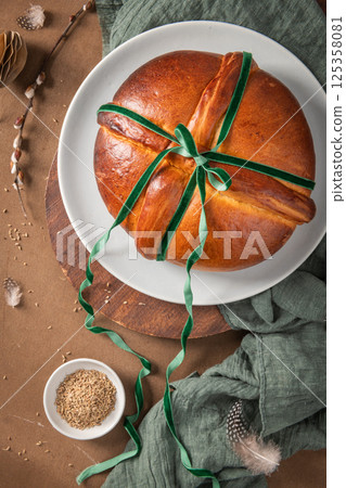 Portuguese traditional Easter cake Folar without eggs on easter table with a green velvet bow and a bowl of fennel seeds. Top view 125358081