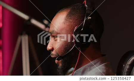 Close up of gamer having fun by competing in online multiplayer videogame, using headset mic. Man laughing while playing on gaming PC, talking with mates through headphones microphone, camera A Close up of gamer having fun by competing in online multiplayer videogame, using headset mic. Man laughing while playing on gaming PC, talking with mates through headphones microphone, camera A 125358427