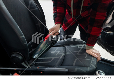 Cleaning the interior of the car with a vehicle vacuum cleaner. 125358453
