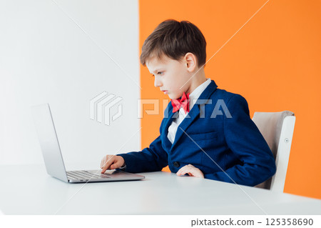 Boy in school uniform working on laptop 125358690
