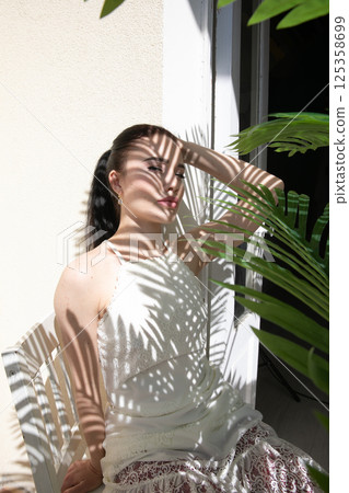 Beautiful brunette woman in summer sitting in the shade of a palm tree 125358699