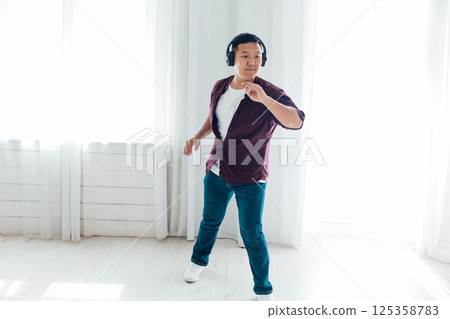 Man in headphones listening to music dancing 125358783