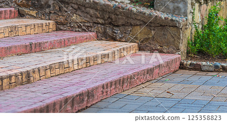 Descending stairs of a street sidewalk, paved with paving slabs, empty, without people. Blank for design, artwork, symbolic sign - a decrease in the level of development 125358823