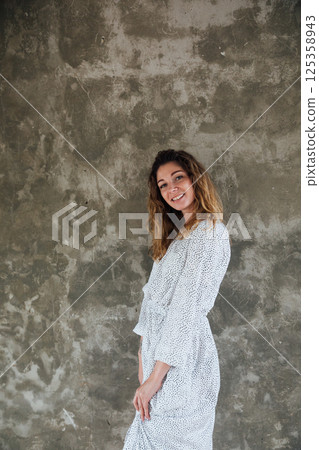 woman in summer white dress smiling on gray background woman in summer white dress smiling on gray background 125358943