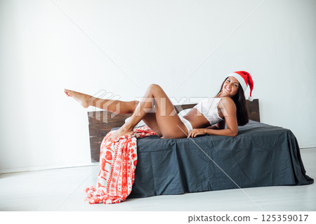 Woman in lingerie in christmas hat in bedroom on bed for new year Woman in lingerie in christmas hat in bedroom on bed for new year 125359017