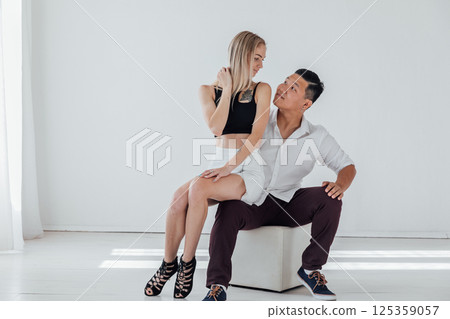 Asian man and blonde woman sitting and hugging together 125359057