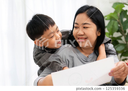 Back to School and Family Bonding. A joyful moment between a mother and her son as they share artwork and smiles. 125359336