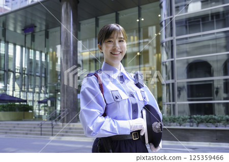 一名年輕的女保全站在辦公大樓前。照片由東京電子專門學校、電波學園株式會社提供。 125359466