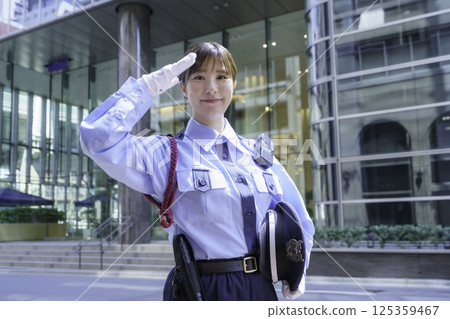 A young female security guard saluting in front of an office building. Photo courtesy of Tokyo Electronics College, Denpa Gakuen Corporation. 125359467