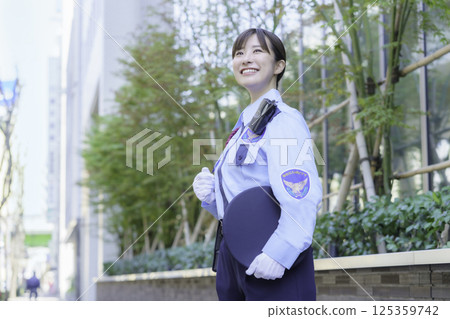 A young female security guard standing in front of an office building. Photo courtesy of Tokyo Electronics College, Denpa Gakuen Corporation. 125359742