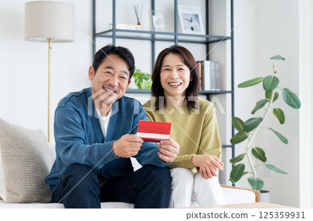 A middle-aged couple looking at their bankbook in the living room A middle-aged couple looking at their bankbook in the living room 125359931