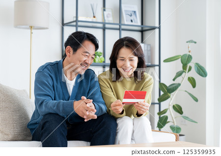 一對中年夫婦在客廳看著他們的存摺 一對中年夫婦在客廳看著他們的存摺 125359935