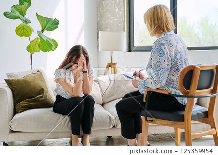 Unhappy sad middle aged woman in therapy session in psychologist therapist office Unhappy sad middle aged woman in therapy session in psychologist therapist office 125359954