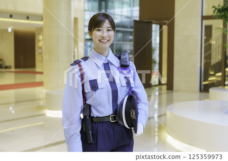 A young female security guard standing in the lobby of an office building. Photo courtesy of Tokyo Electronics College, Denpa Gakuen Corporation. 125359973