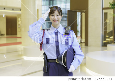 一名年輕的女保全在辦公大樓大廳敬禮。照片由東京電子專門學校、電波學園株式會社提供。 125359974