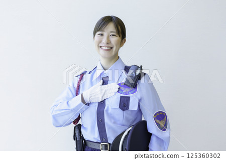 Portrait of a young female security guard with her hand on her chest against a white background. Photo courtesy of Tokyo Electronics College, Denpa Gakuen Corporation 125360302