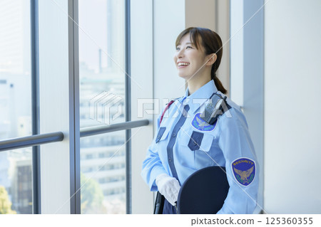 Portrait of a young female security guard standing by a window. Photo courtesy of Tokyo Electronics College, Denpa Gakuen School Corporation. 125360355