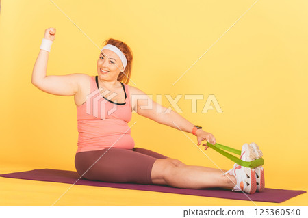 A woman is doing a yoga pose with a green resistance band A woman is doing a yoga pose with a green resistance band 125360540