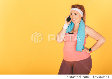 A woman is talking on her cell phone while wearing a blue towel A woman is talking on her cell phone while wearing a blue towel 125360541