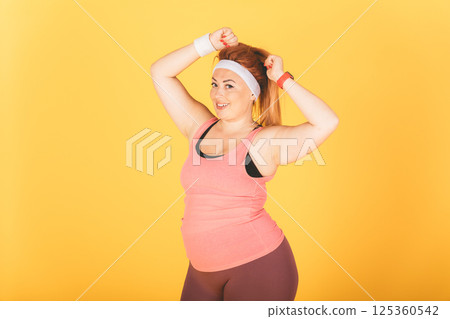 A woman in a pink tank top and black shorts is posing for a picture A woman in a pink tank top and black shorts is posing for a picture 125360542