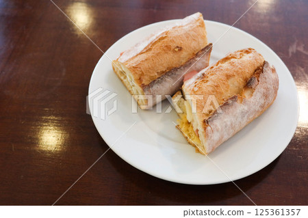 close up of a Baguette bread sandwich with ham and cheese cut in two half on a white plate with copy space close up of a Baguette bread sandwich with ham and cheese cut in two half on a white plate with copy space 125361357