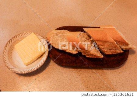 close up of a baguette bread cut into piece, with a small block of butter on the side close up of a baguette bread cut into piece, with a small block of butter on the side 125361631