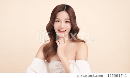 A beautiful young Asian woman with clean, fresh skin against a beige background. Skincare, facial treatment, cosmetology, beauty, and spa. An elegant portrait of an Asian woman. A beautiful young Asian woman with clean, fresh skin against a beige background. Skincare, facial treatment, cosmetology, beauty, and spa. An elegant portrait of an Asian woman. 125361741