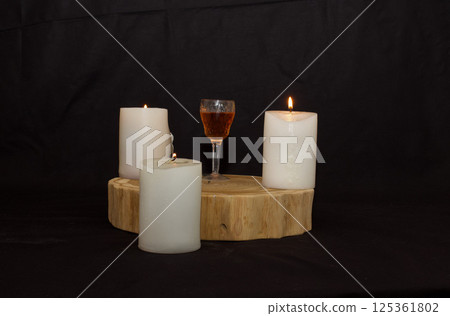 three burning candles on the oak stand with a glass of homemade strong drink  in the dark on the eve of the Christian Easter holiday in spring 125361802