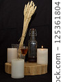 three burning candles on the oak stand with a glass of homemade strong drink and wheat 125361804