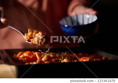 A close-up view of a cooked dish with beans and fresh rosemary, served in warm lighting. The rustic meal highlights natural and wholesome ingredients. Ideal for homemade cooking concepts. 125361870