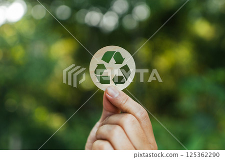 Sustainable environment recycling and nature conservation Hand with recycling sign natural blur background Sustainable environment recycling and nature conservation Hand with recycling sign natural blur background 125362290