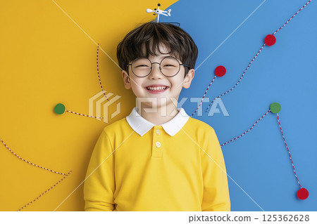 Young boy wearing glasses and a yellow shirt is smiling 125362628