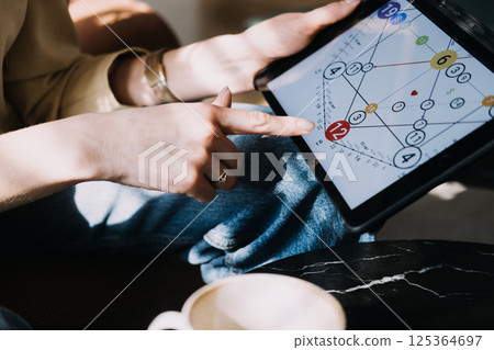 Numerologist analyzing a personal numerology chart on a tablet in a calm setting. Modern numerology, digital chart reading, intuitive guidance, spiritual technology... 125364697
