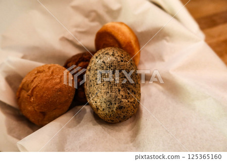 close up of assortment of different breads nestled in a piece of white parchment paper cloth in a basket with copy space close up of assortment of different breads nestled in a piece of white parchment paper cloth in a basket with copy space 125365160