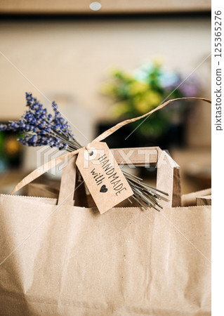 A brown paper gift bag with a Handmade with love tag and a sprig of dried lavender attached. Handmade gifts, small business packaging, craft market appeal, eco-conscious branding A brown paper gift bag with a Handmade with love tag and a sprig of dried lavender attached. Handmade gifts, small business packaging, craft market appeal, eco-conscious branding 125365276
