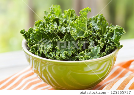 Fresh green kale in a bowl on striped cloth. Fresh green kale in a bowl on striped cloth. 125365737