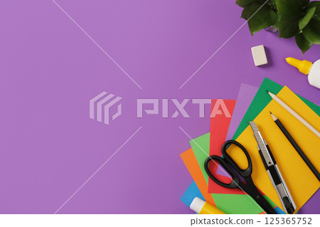 Creative accessories: scissors, craft knife, pencil, eraser, paper on purple background. Space for your text. A work table for paper crafts. Creative accessories: scissors, craft knife, pencil, eraser, paper on purple background. Space for your text. A work table for paper crafts. 125365752