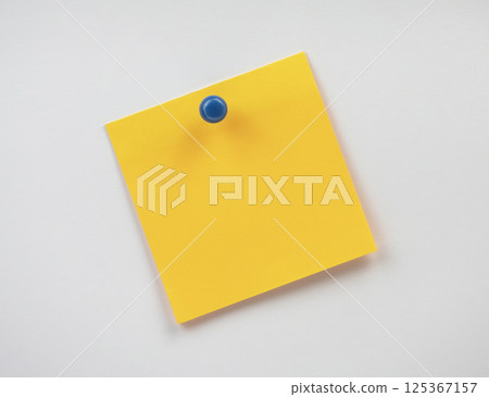 A yellow sticky note is attached to a wall, ready for reminders or notes 125367157