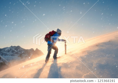 Adventurer hiking with sunrise on snowy mountain amidst the snowstorm at Norway 125368191