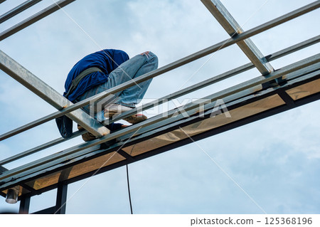 Construction worker installing metal framework on building site 125368196
