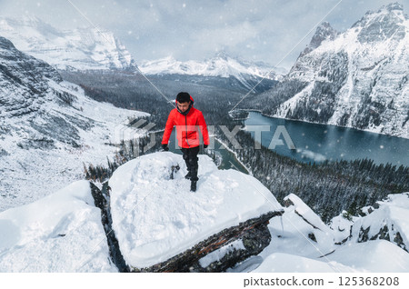 Asian male tourist standing on Opabin Plateau with snowy Rocky Mountains and Lake Ohara in Yoho national park at Canada 125368208