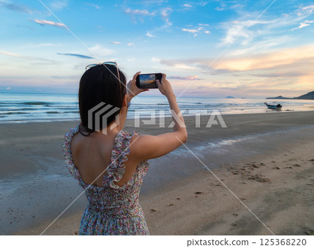 Asian woman taking a photo with mobile phone of tropical sea on the beach Asian woman taking a photo with mobile phone of tropical sea on the beach 125368220