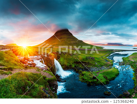 Vibrant sunset over volcanic Kirkjufell mountain and dramatic sky in summer at Snaefellsnes peninsula, Iceland Vibrant sunset over volcanic Kirkjufell mountain and dramatic sky in summer at Snaefellsnes peninsula, Iceland 125368240