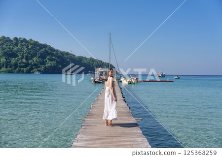 Asian woman enjoying on wooden pier among tropical sea on sunny day at Koh Kood 125368259