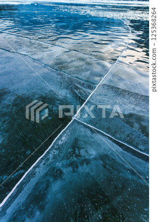 Natural cracked frozen lake surface with deep blue reflection Natural cracked frozen lake surface with deep blue reflection 125368264