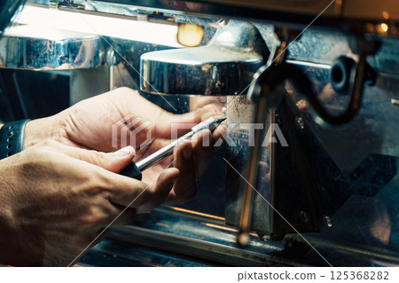 Technician using screwdriver removing nut from coffee maker in coffee shop 125368282