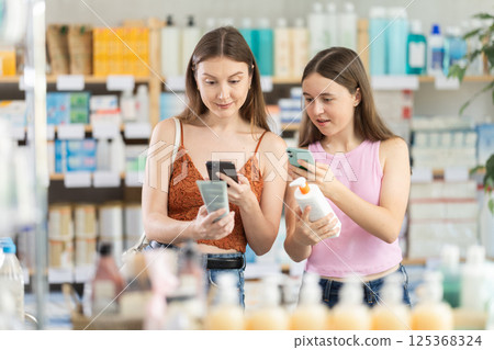 European woman and her daughter scan the barcode of a cream 125368324