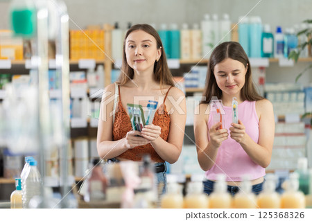 Woman with daughter choosing toothbrush in pharmacy Woman with daughter choosing toothbrush in pharmacy 125368326