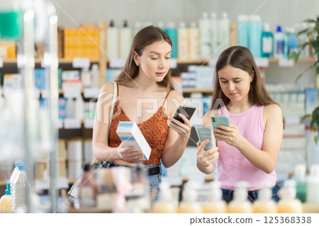 Woman with daughter scanning qr code of cream Woman with daughter scanning qr code of cream 125368338